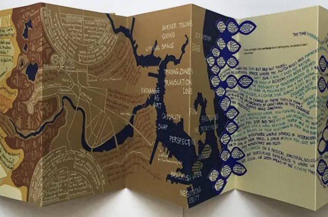 An accordion-fold artist book featuring layered maps, handwritten text, and abstract river-like shapes in earthy tones of brown, tan, and navy blue. The pages combine cartographic imagery with poetic words and phrases, exploring themes of borders, translation, exchange, and perspective.