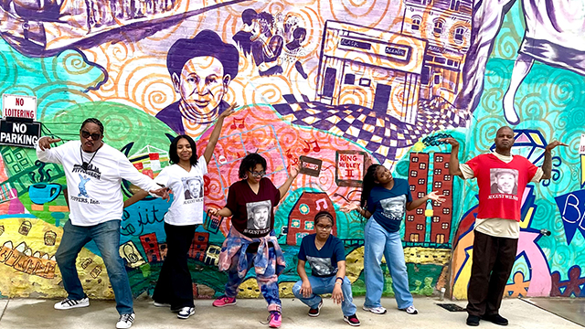 hip hop dancers wearing an august wilson dedication tshirts in front of the august wilson mural
