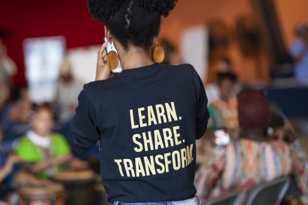 Woman wearing a shirt that says "Learn. Share. Transform."