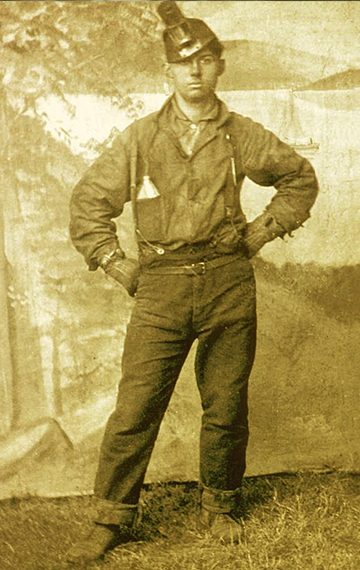 This miner is wearing an early torch style lamp on his cap and is carrying a blasting powder flask in his shirt pocket.